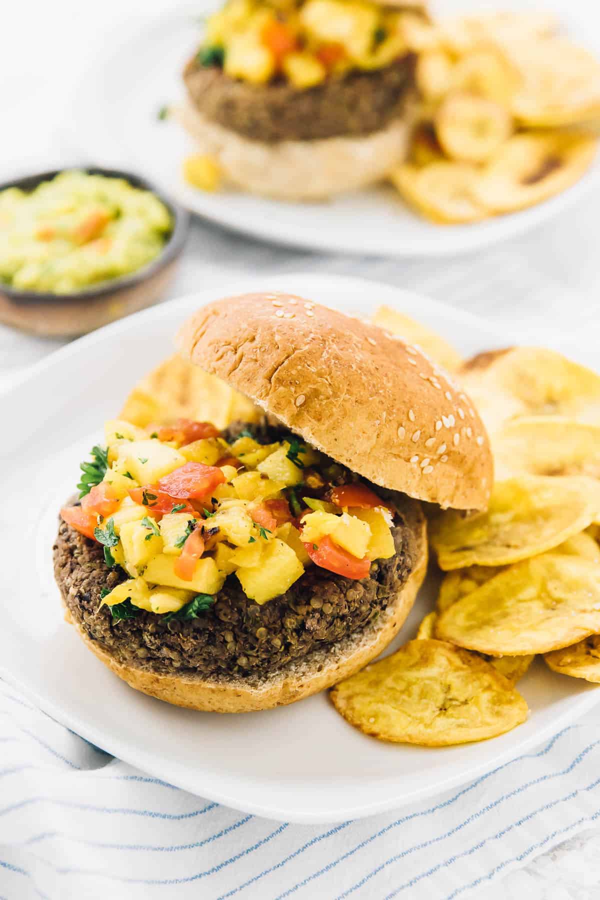 A burger with pineapple salsa and chips on the side. 