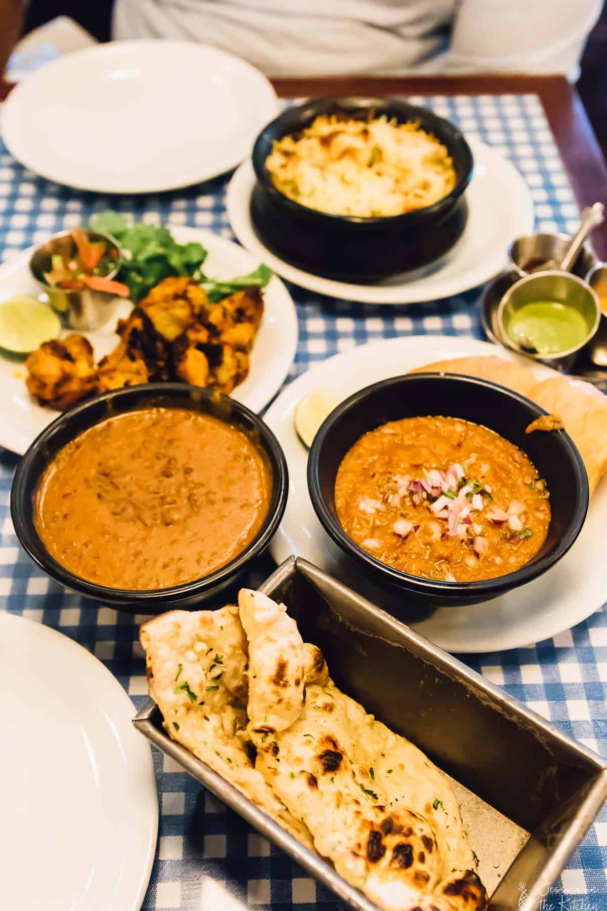 A table spread with bowls of curry and naan bread. 