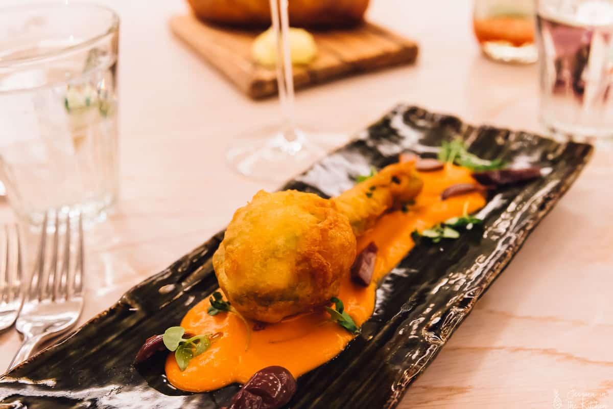 Fried zucchini blossom on a black dish.