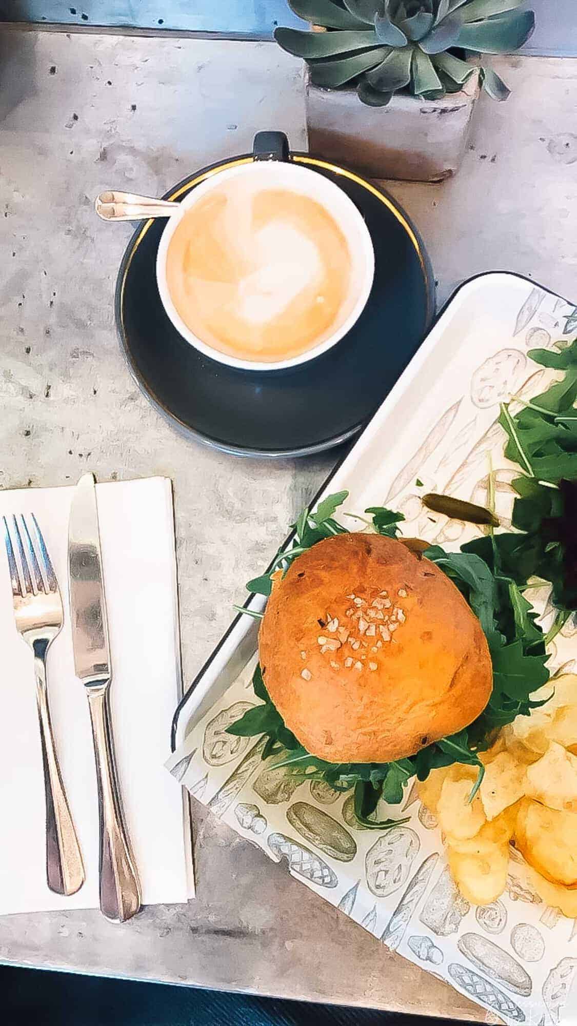 Top down view of a burger and coffee on a table. 