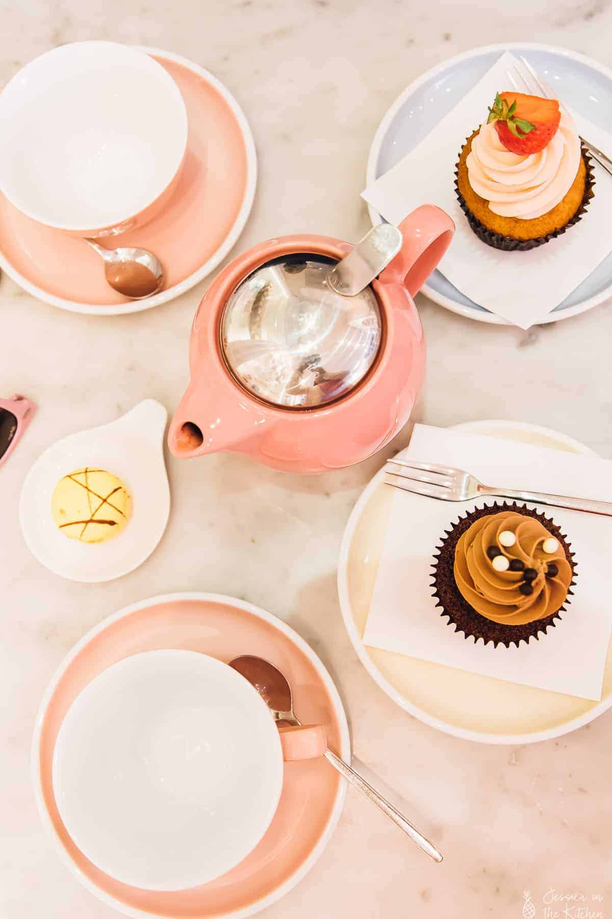 Top down view of pink cups and cupcakes on a table. 