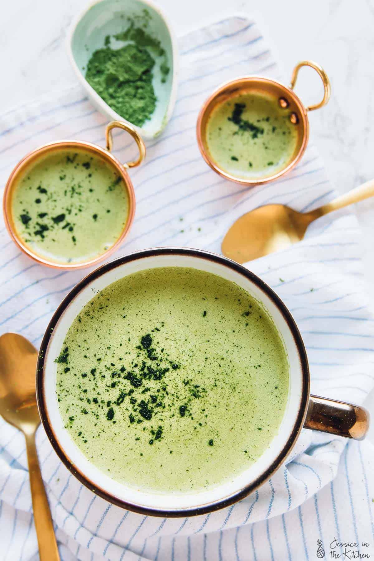 Top down view of pumpkin spice matcha latte in a cup, on a stripe cloth. 