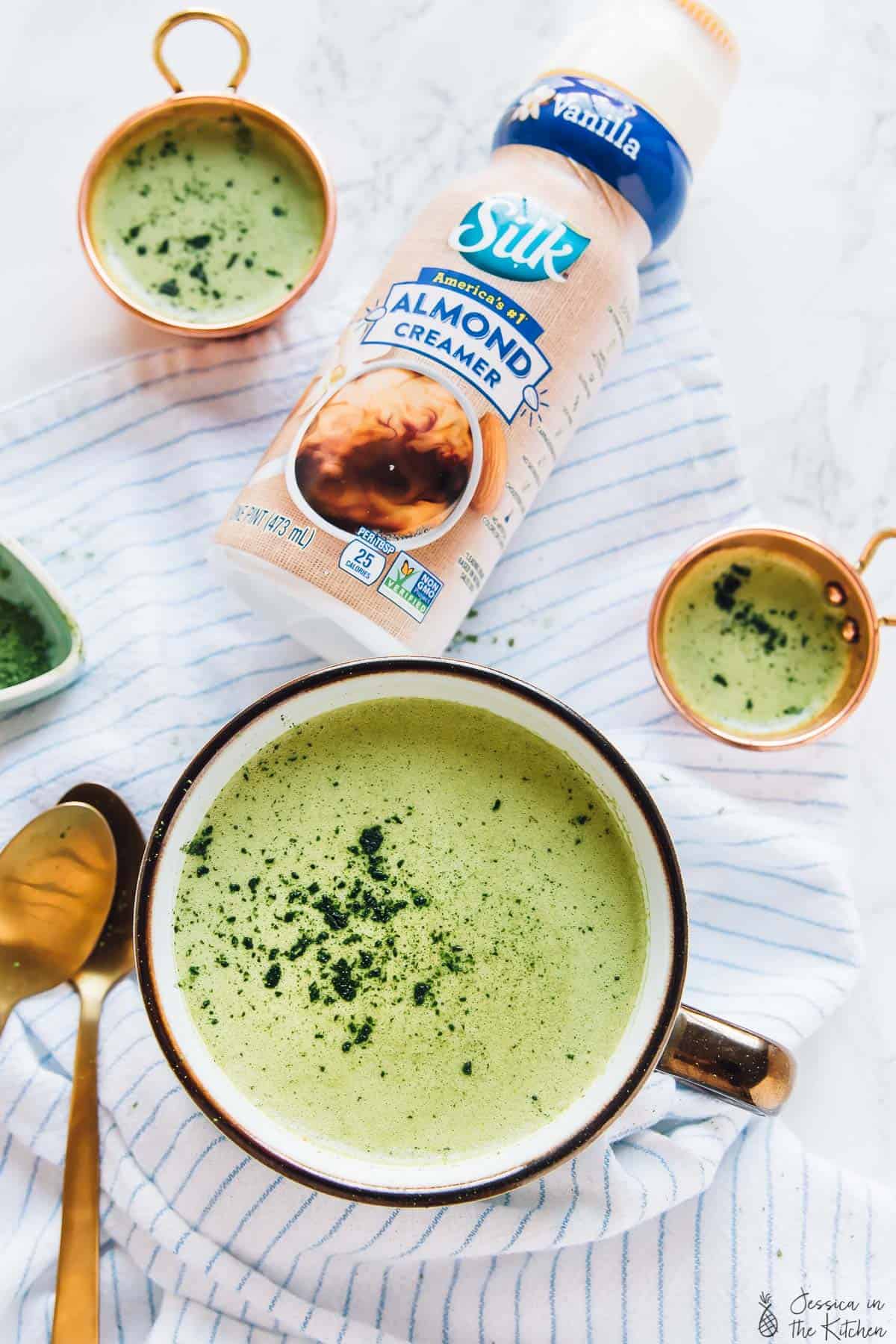 Top down shot of pumpkin spice matcha latte with a bottle of almond creamer next to it. 