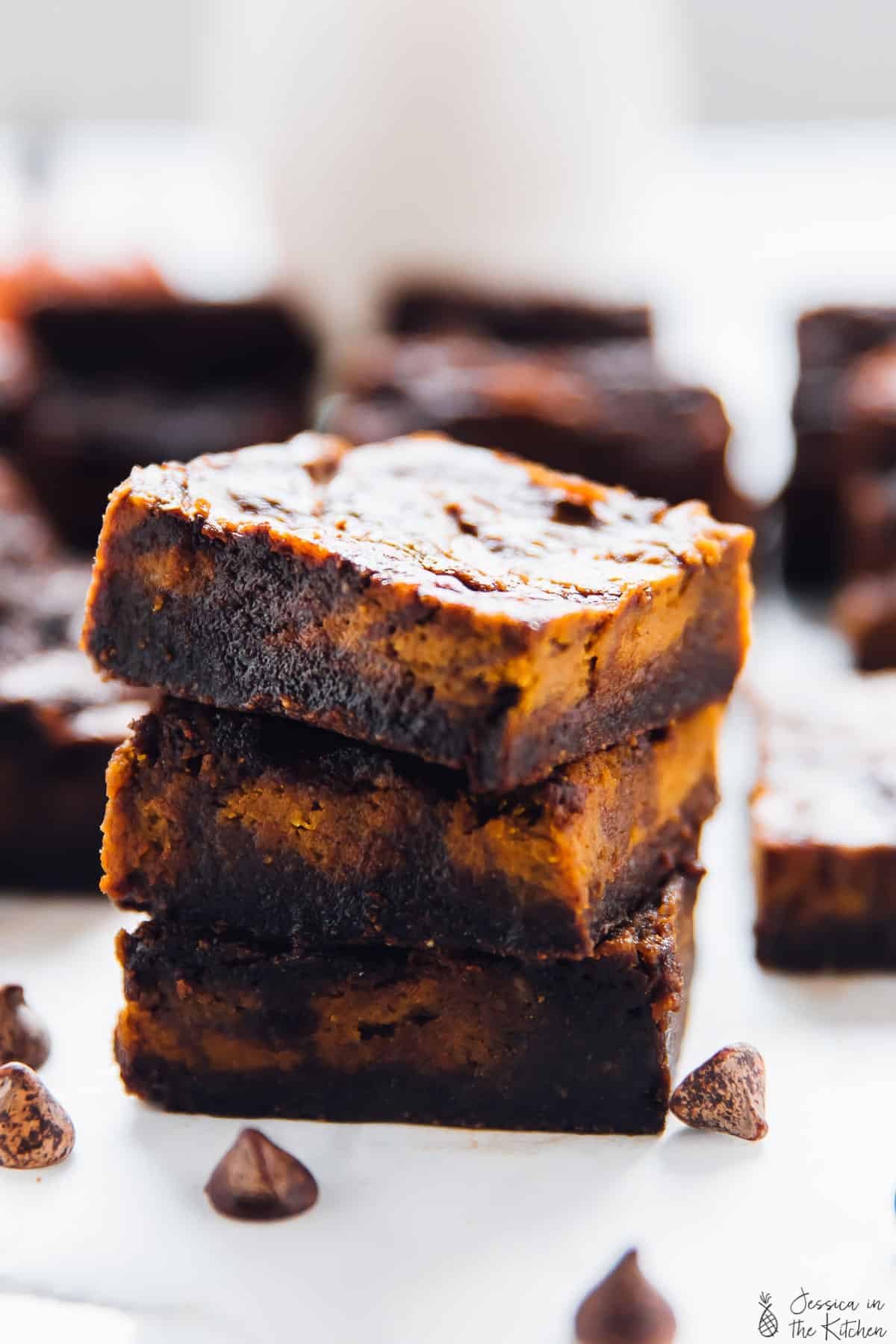 A stack of pumpkin cheesecake swirl brownies on a table. 