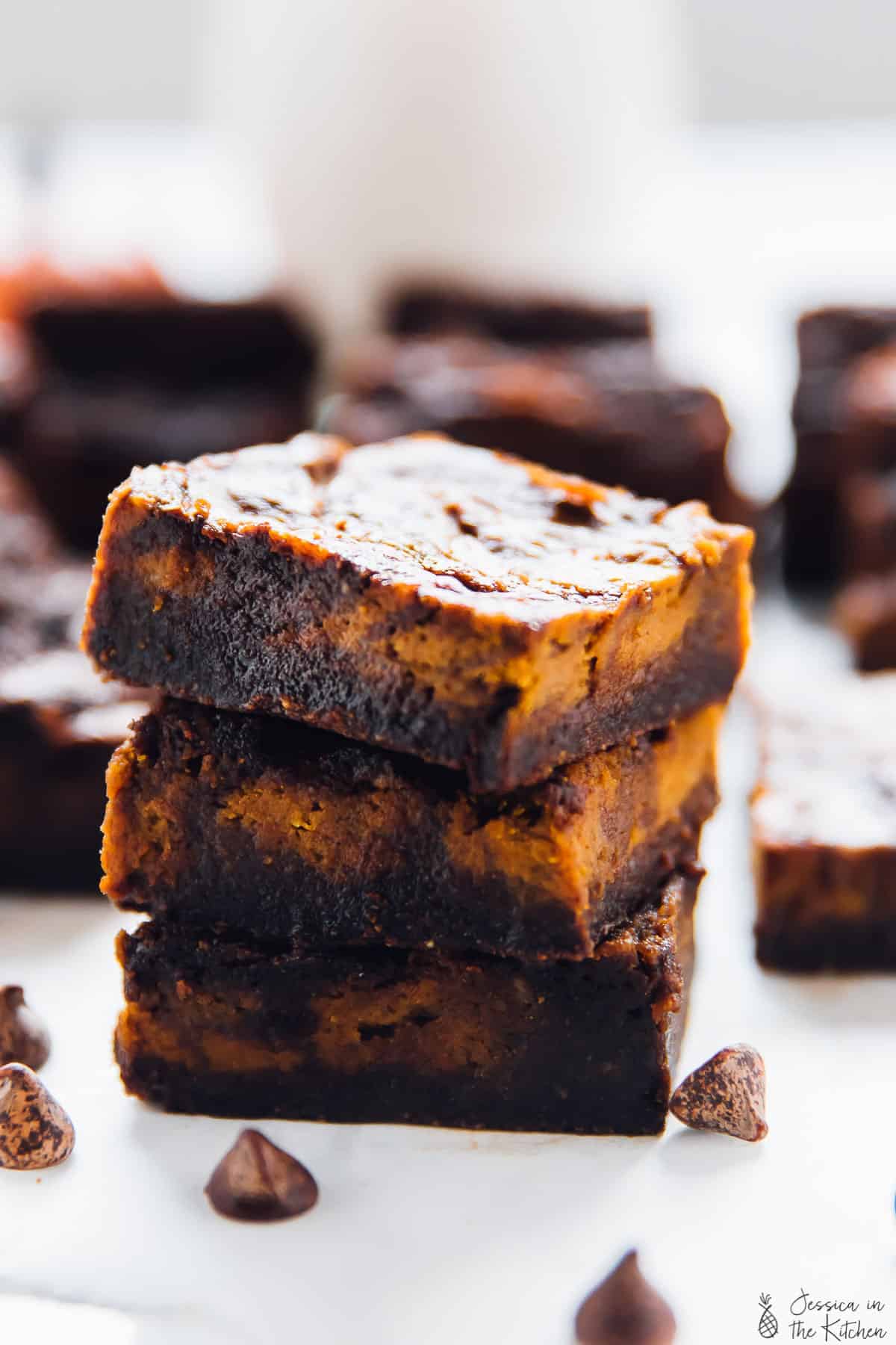 A stack of three squares of brownies with cheesecake swirls