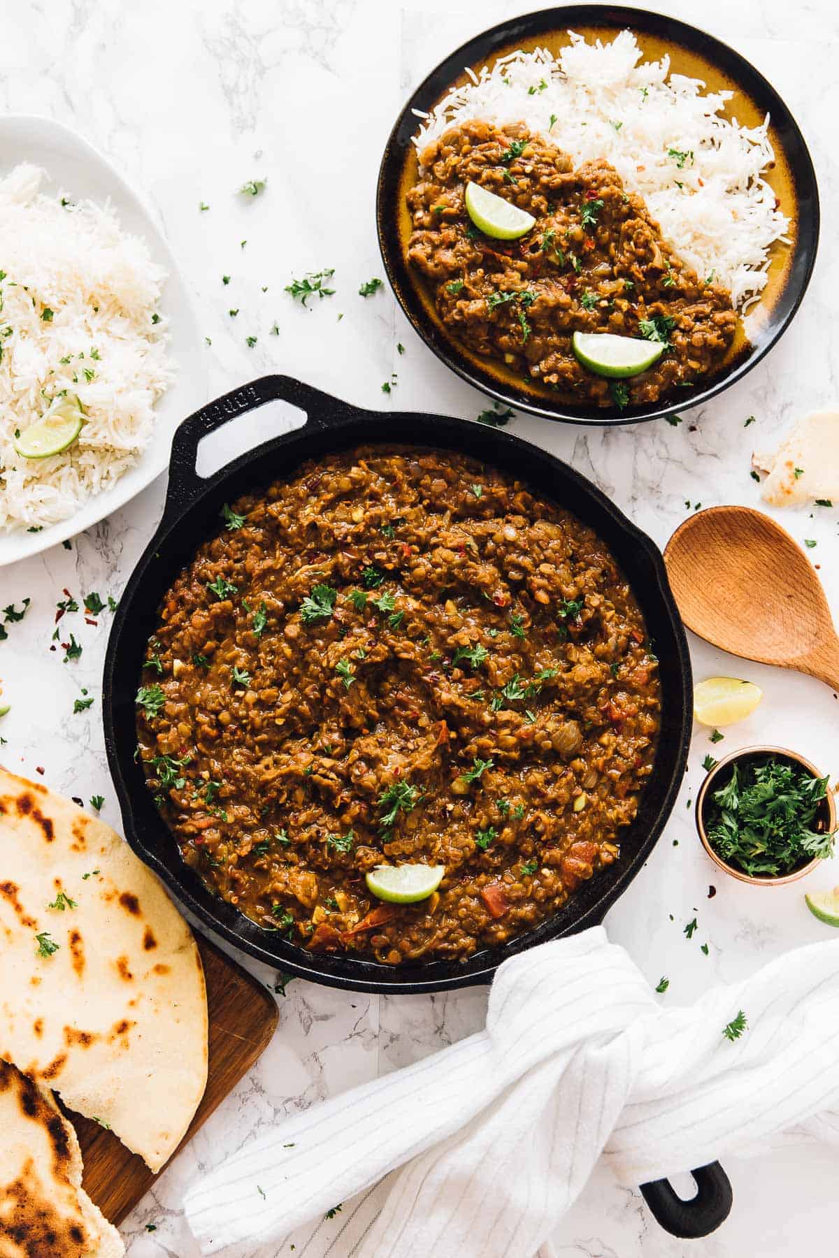 Top down view of red lentil curry in a skillet with naan bread on the side. 