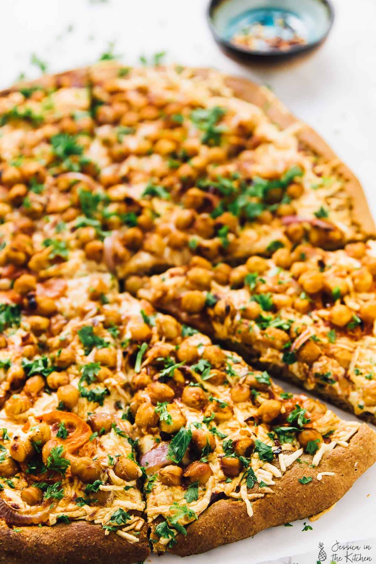 Sliced BBQ chickpea pizza on parchment-lined countertop