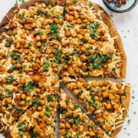 Overhead view of whole spicy BBQ chickpea pizza with two slices pulled away slightly