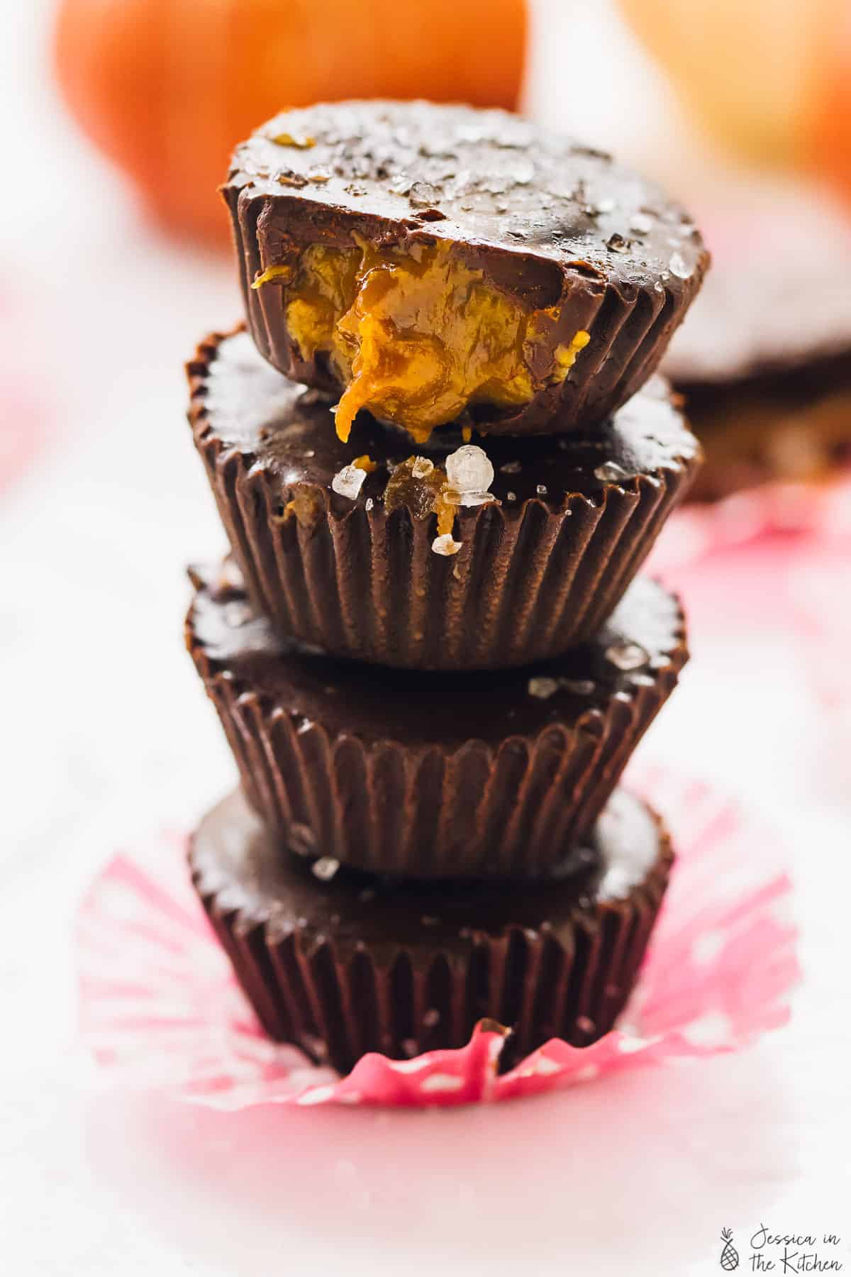 A stack of four salted caramel chocolate cups on a pink liner. 