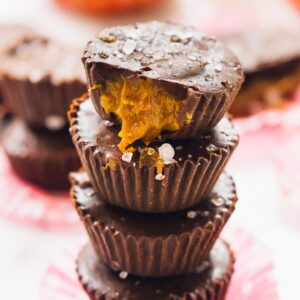 A pile salted caramel chocolate cups on a pink wrapper.