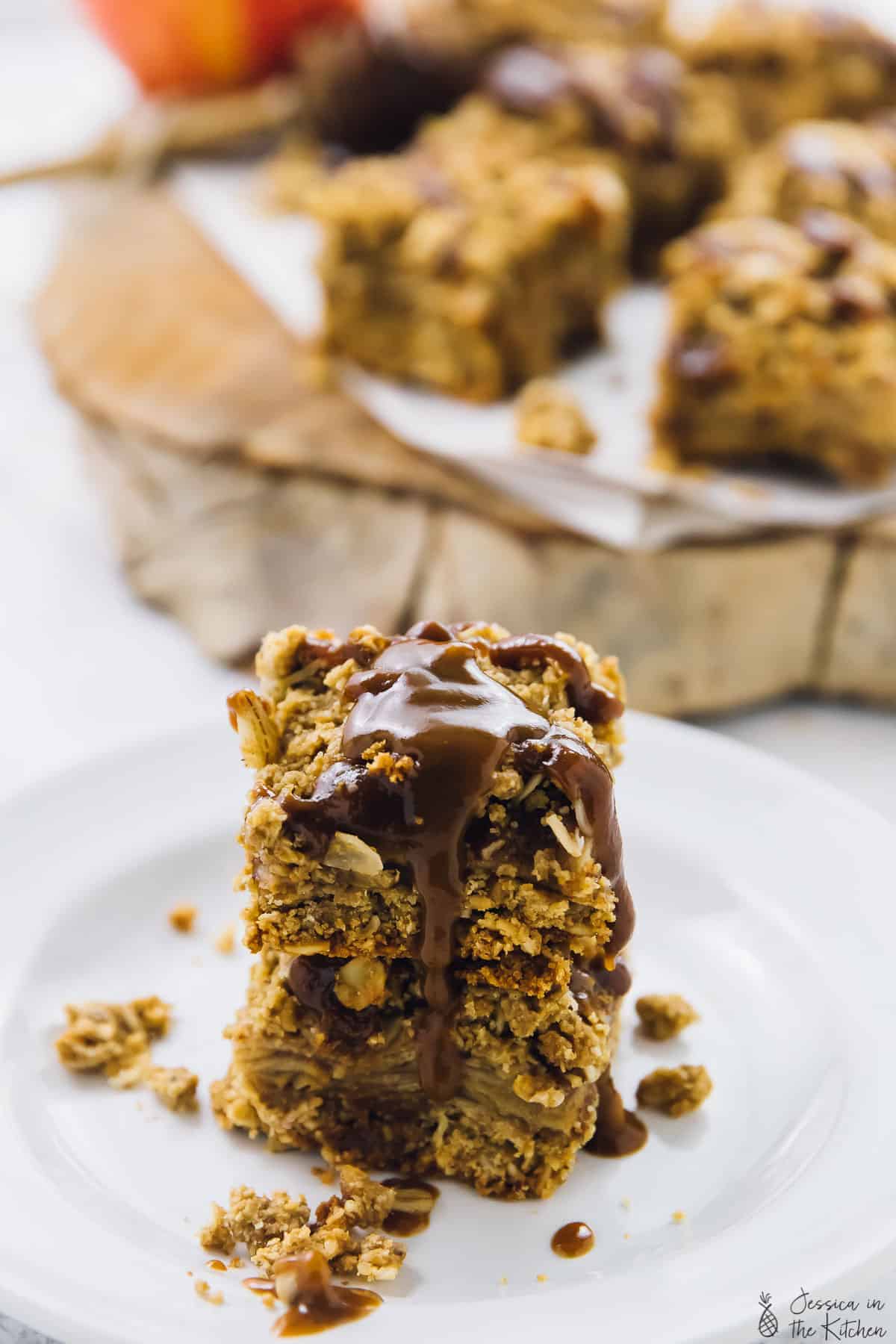 Two apple pie bars drizzled with caramel sauce. 