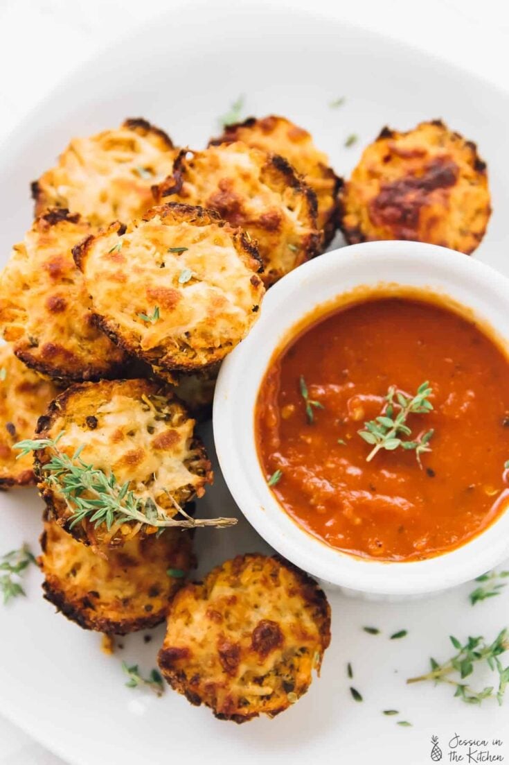 Cauliflower pizza bites with a bowl of tomato sauce next to them.