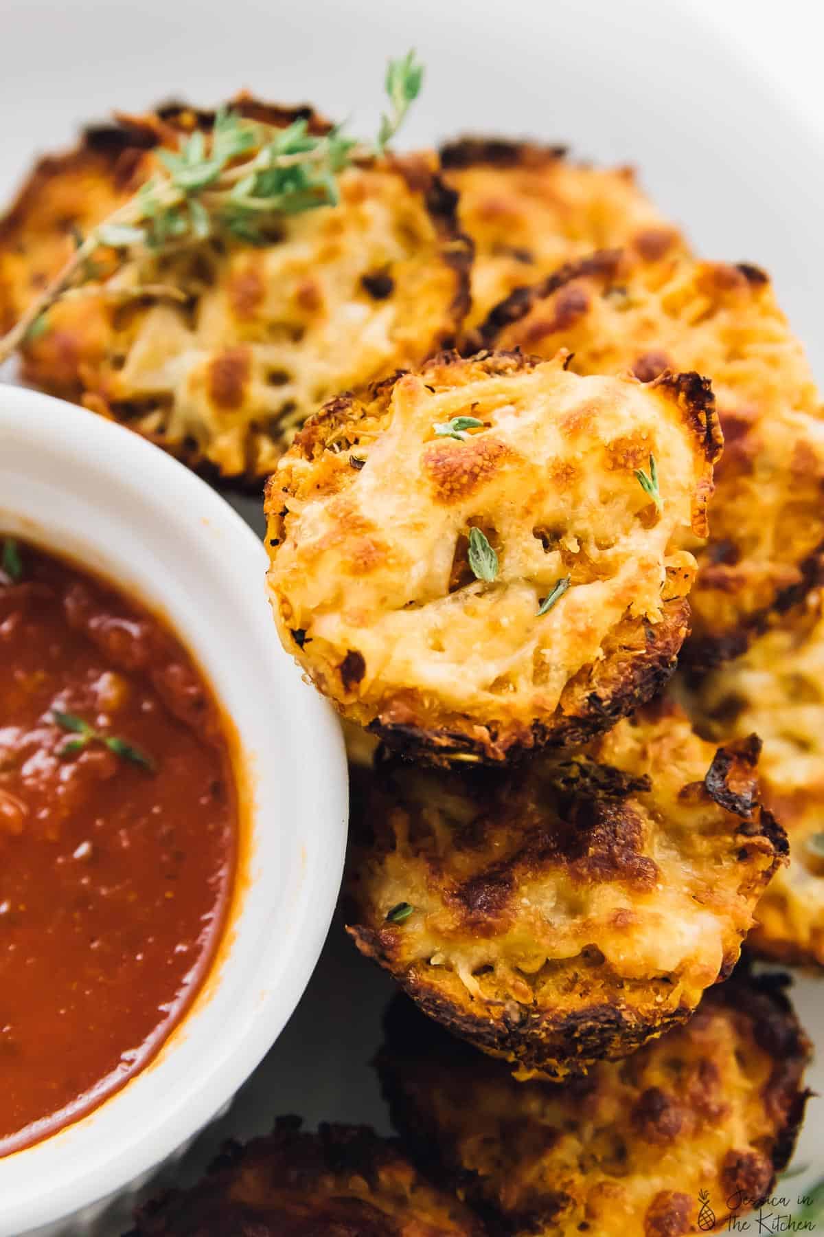 A close up of cauliflower pizza bites next to a dipping sauce. 