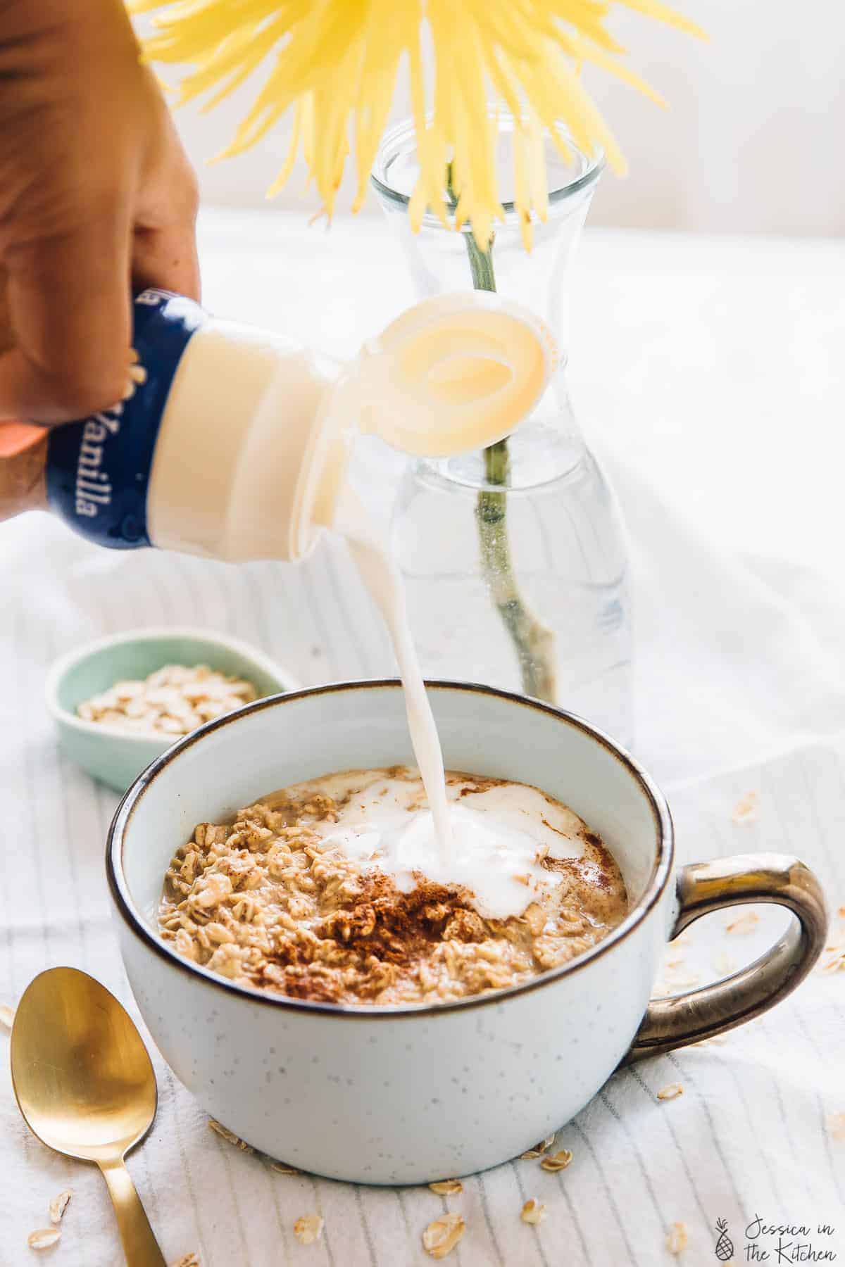 Pouring creamer on a cup of overnight oats. 