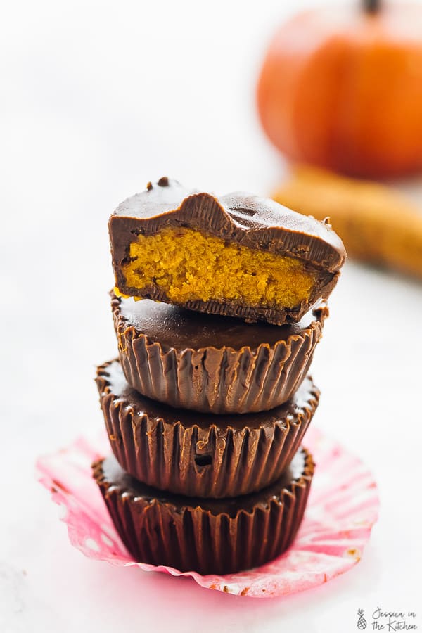 A stack of pumpkin chocolate cups on a pink wrapper. 
