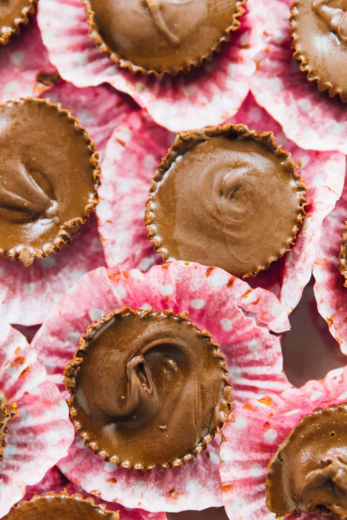 Top down shot of pumpkin chocolate cups on pink liners. 