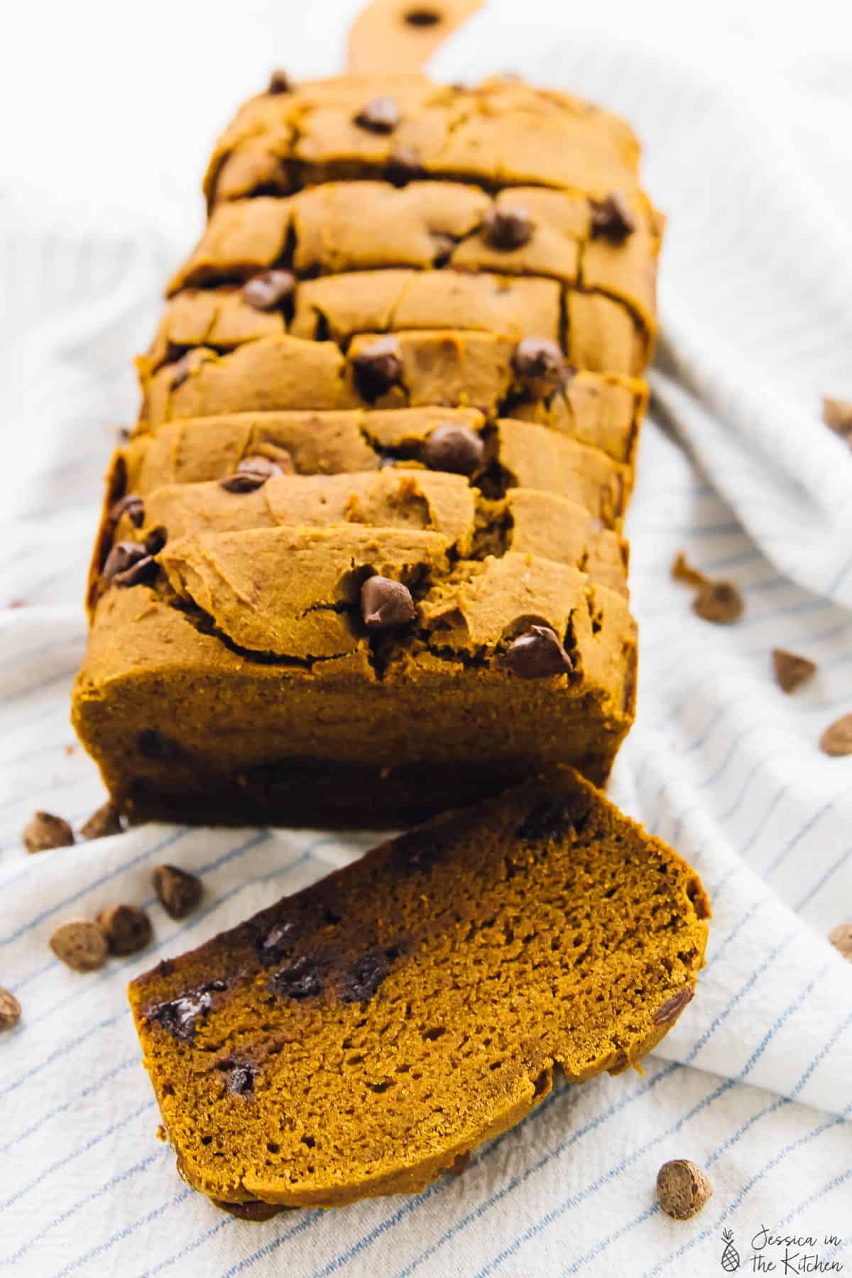 Slices of chocolate chip pumpkin bread on a striped cloth. 