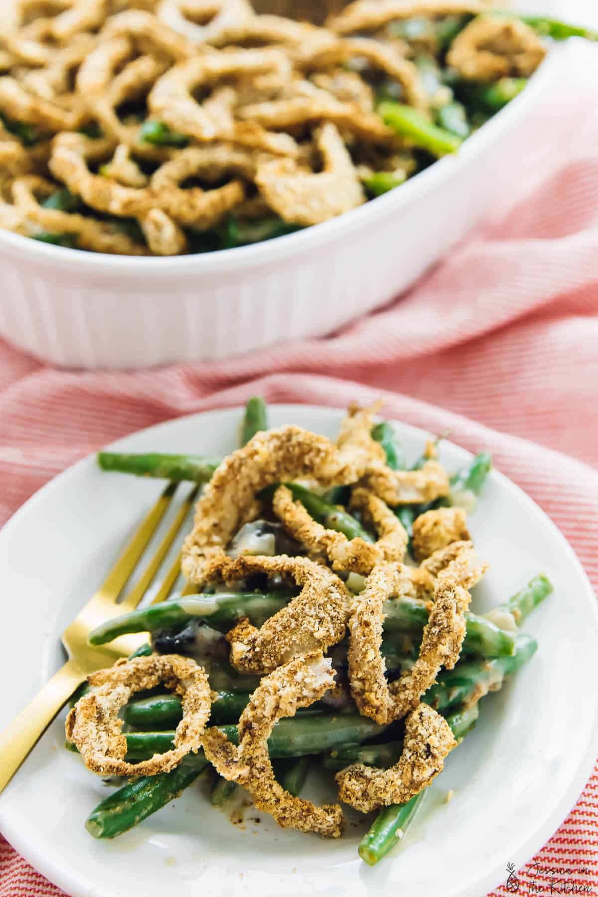 Green bean casserole on a white plate with a gold fork on the side. 