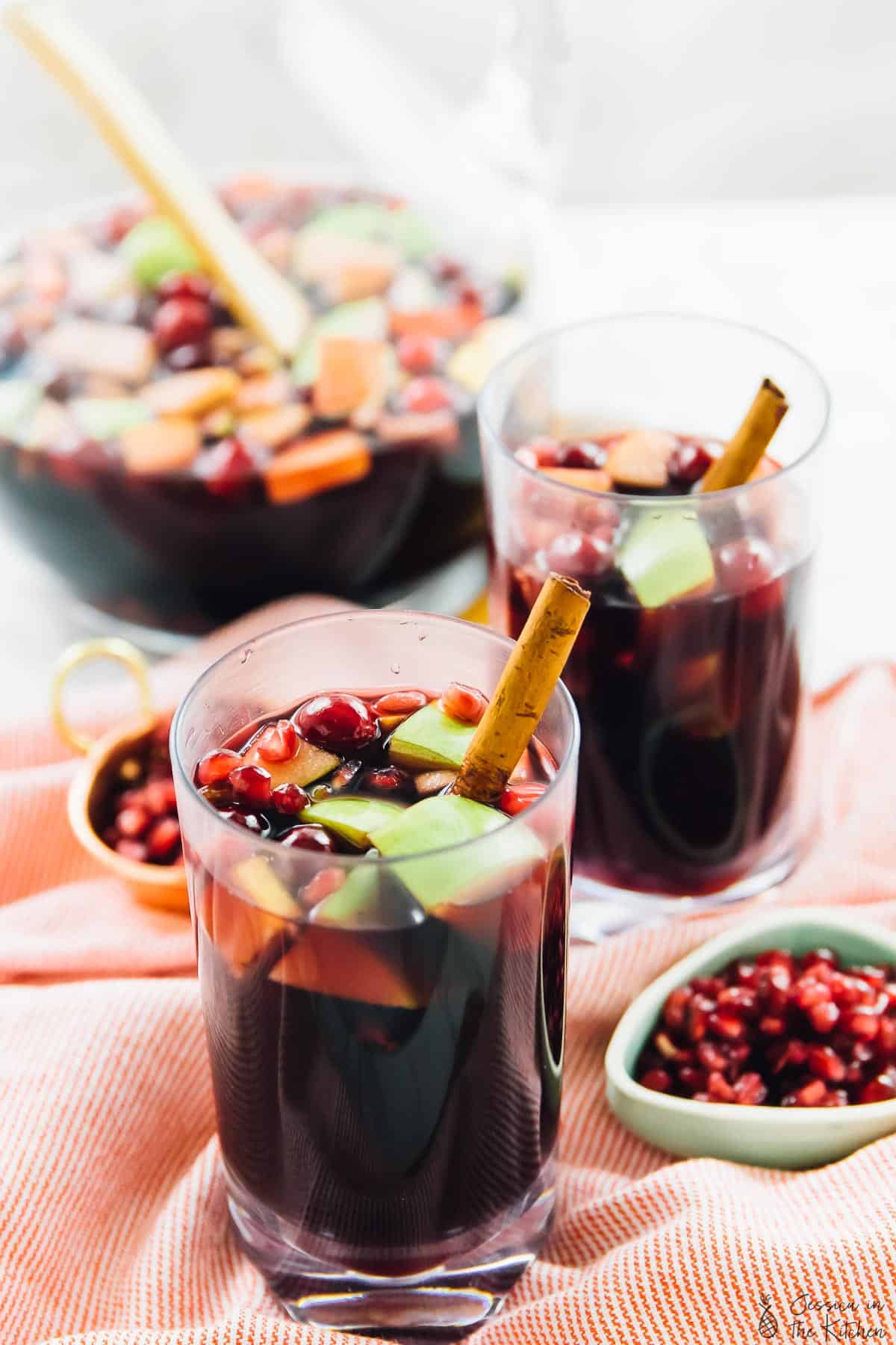 Two glasses of red wine apple cider fall sangria on cloth. 