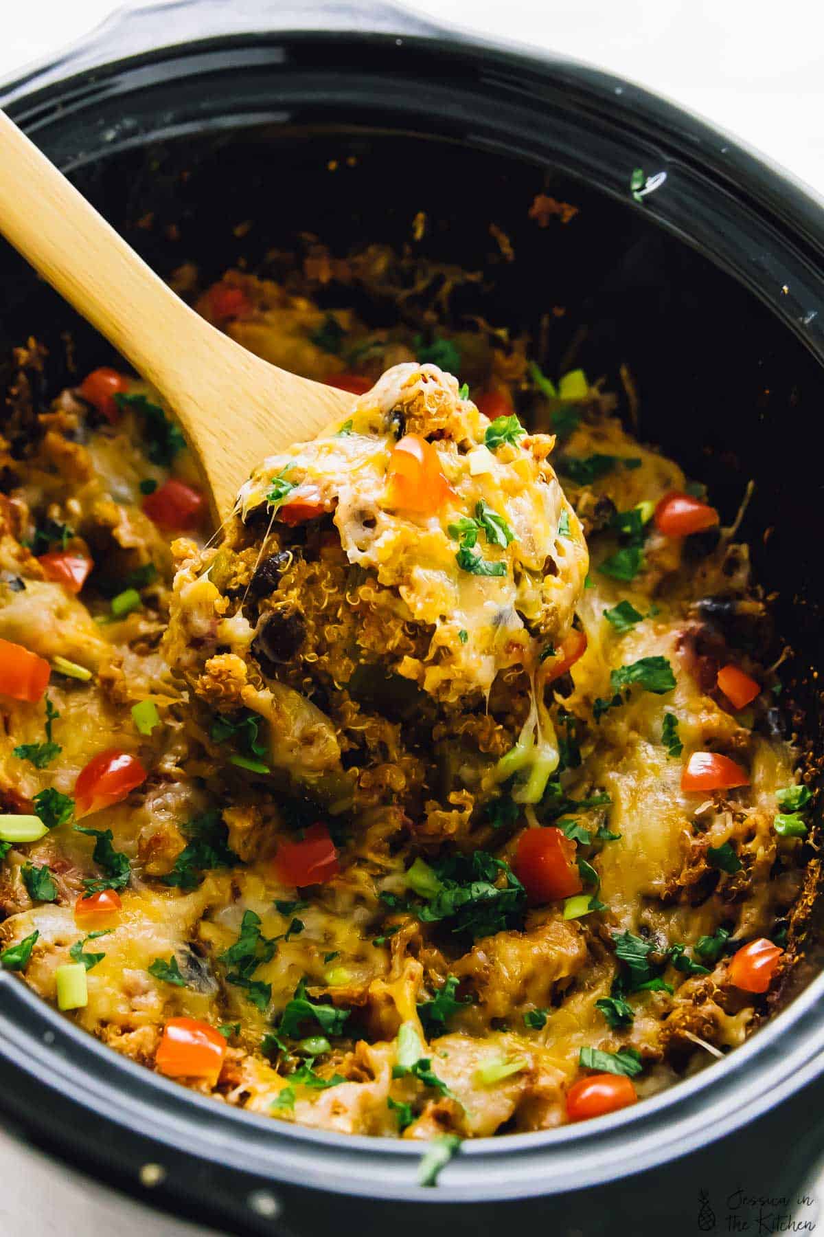 Slow cooker quinoa enchilada casserole being scooped out of a pot. 