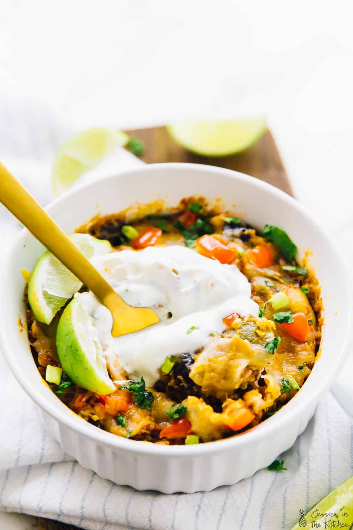 Slow cooker quinoa enchilada casserole in a white ramekin with a gold fork in it. 