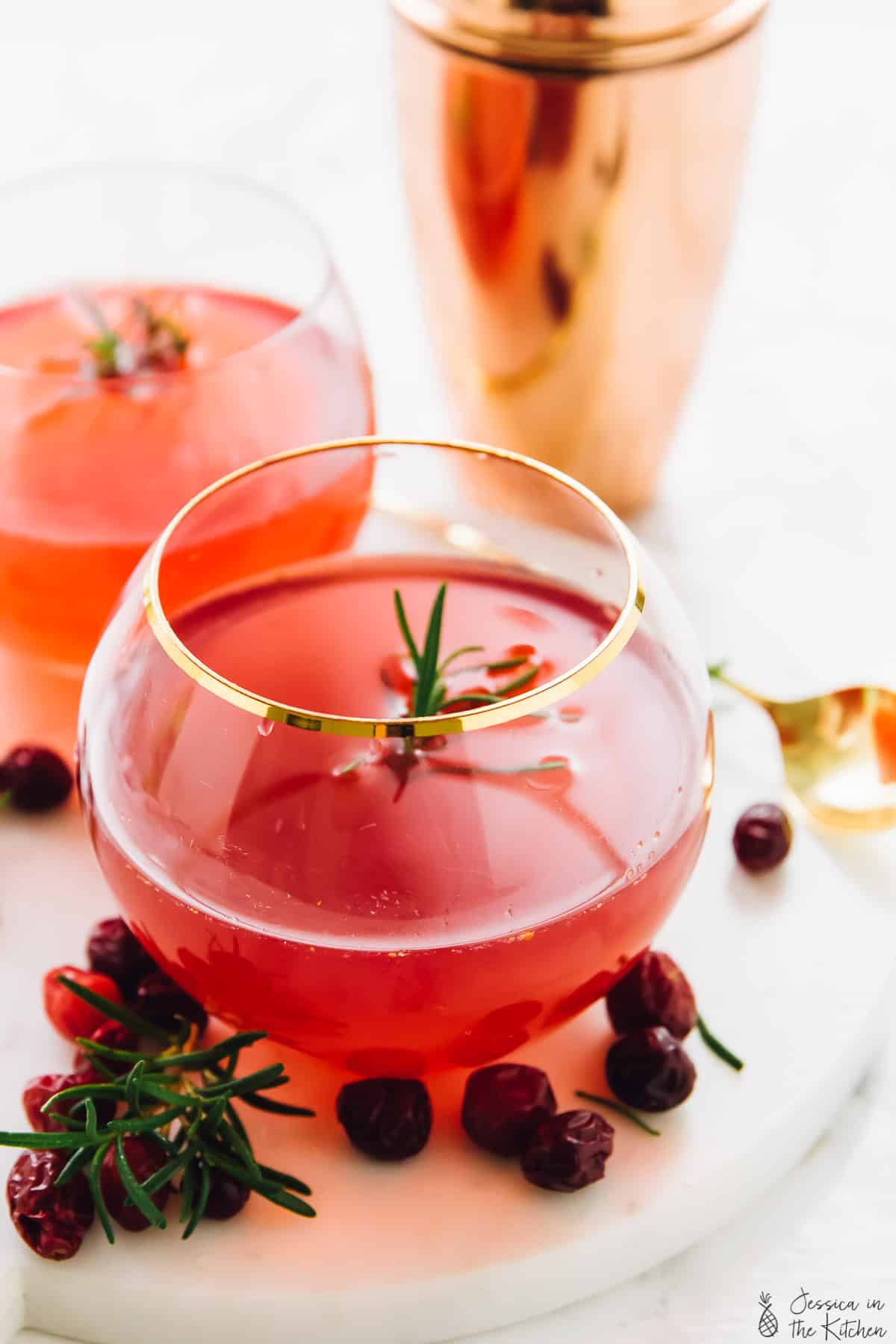 Winter cranberry gin cocktails in round glasses surrounded by loose cranberries. 