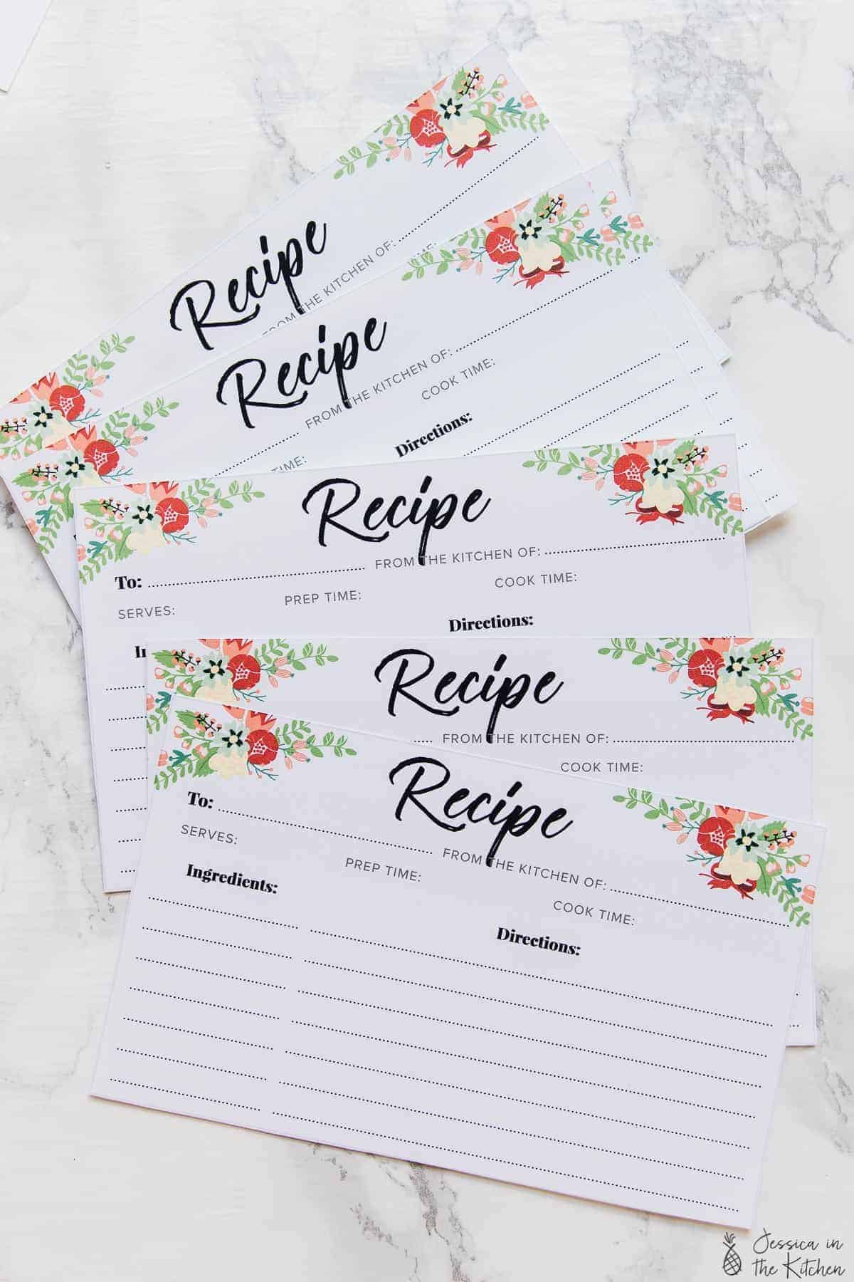 A bunch of printed recipe cards fanned out on a white table.