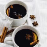Two mugs of mulled wine on a striped cloth.