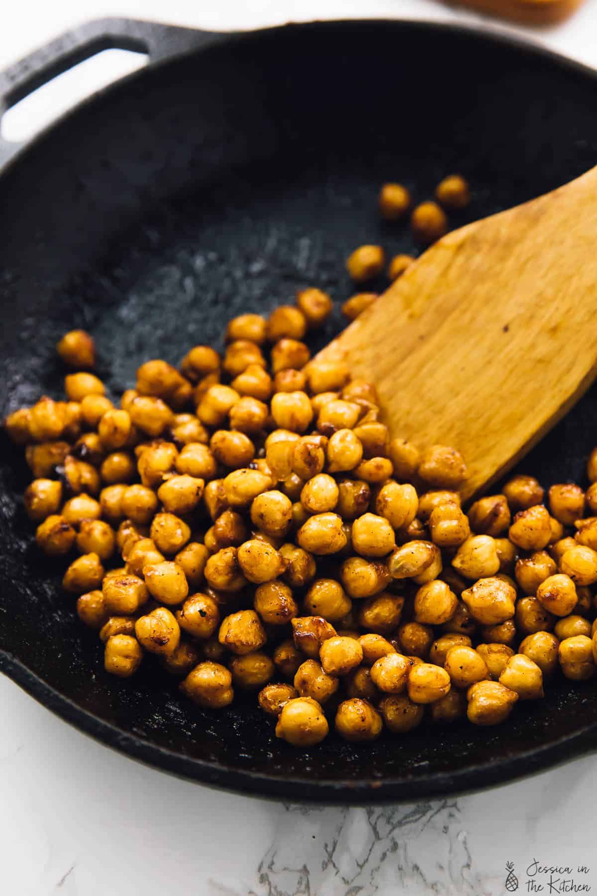 BBQ chickpeas in cast iron skillet with wooden spatula