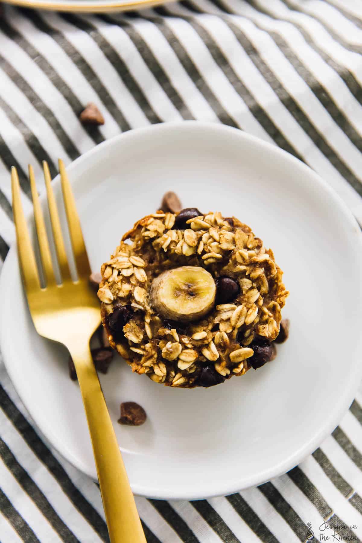 Top down shot of an oatmeal cup on a plate with a gold fork on the side. 