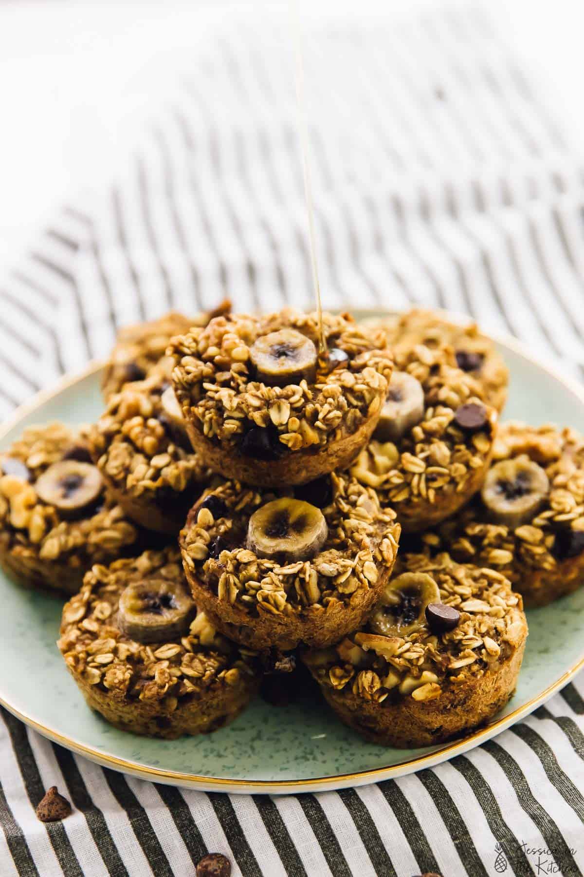 A batch of oatmeal cups on a green plate, being drizzled with honey. 