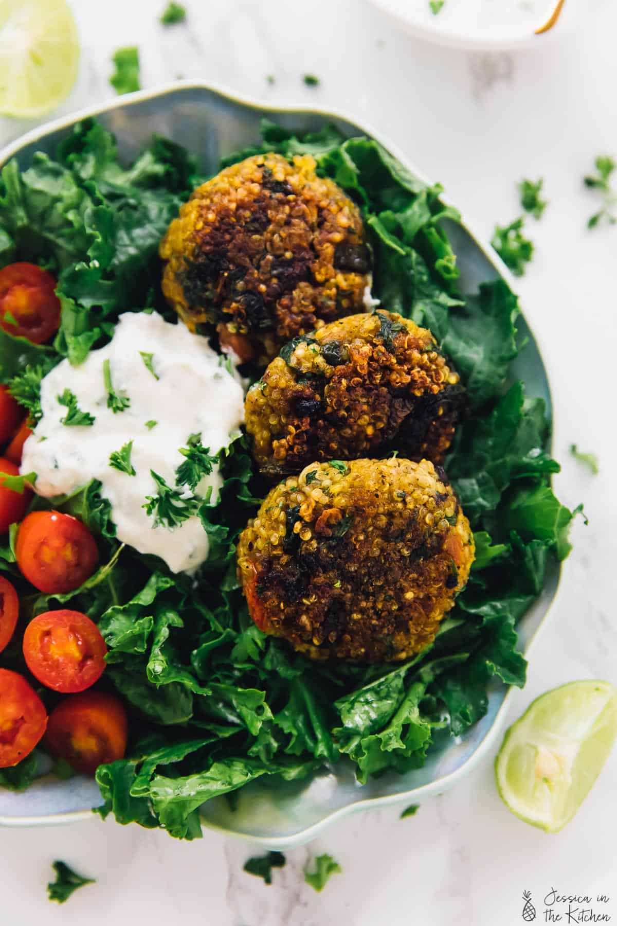 Top down shot of quinoa patties on a bed of greens and tomatoes. 