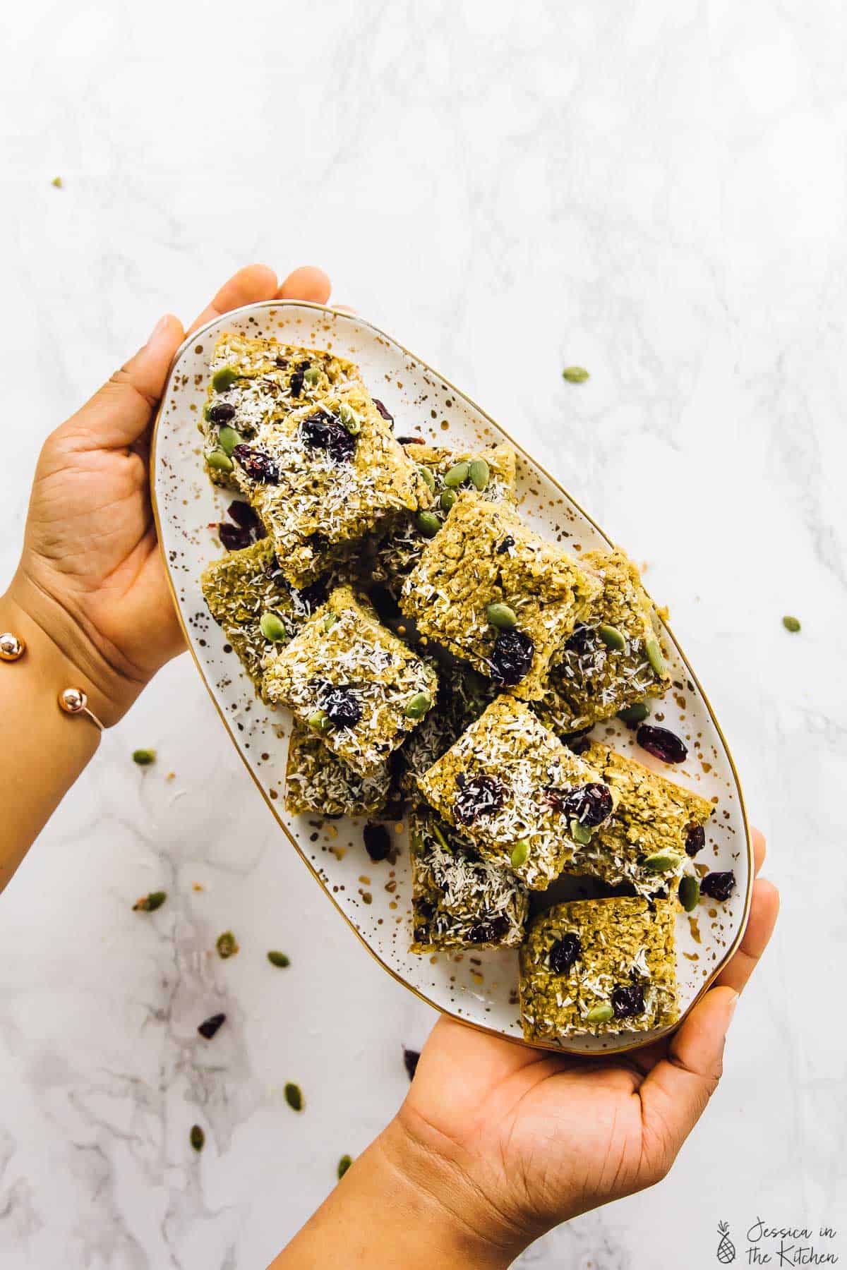 Hands holding a plate of breakfast bars. 