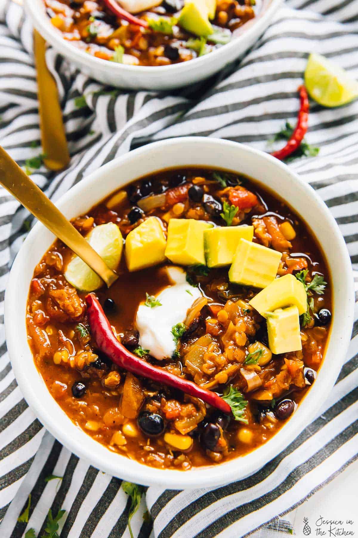 Top down view of red lentil chili topped with avocado.