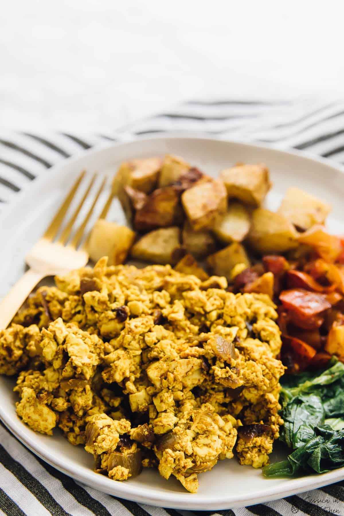 Close up of tofu scramble on a plate with potatoes and veggies. 