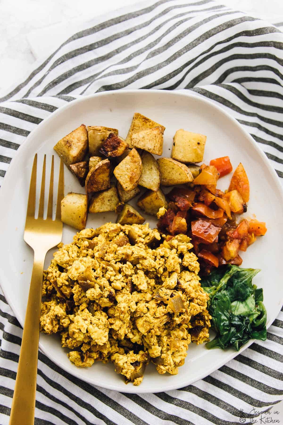 Tofu scramble on a plate with potatoes and veggies. 