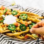 A hand picking up a vegan nacho cheese fry.