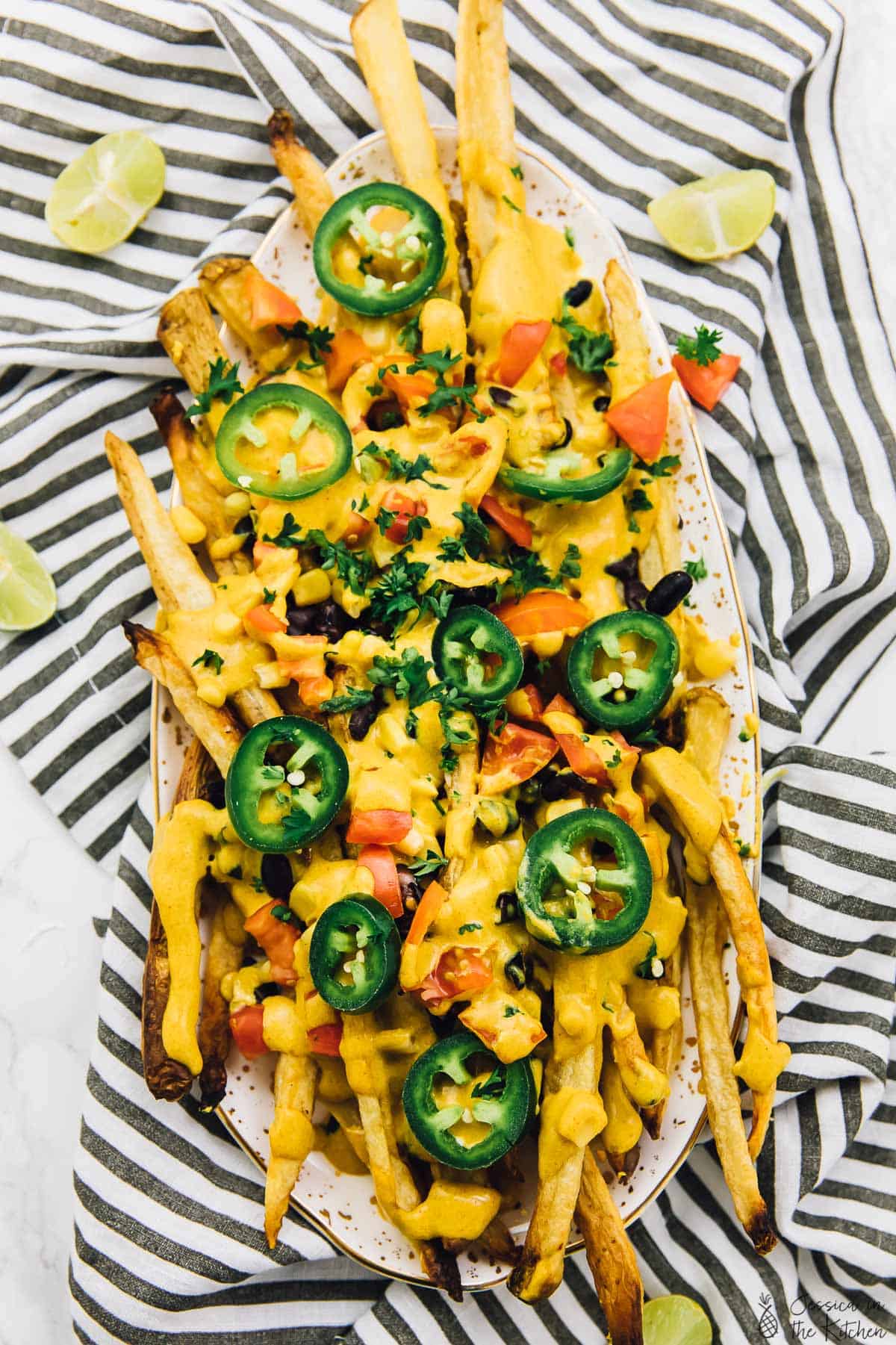 Top down view of vegan nacho cheese fries with wedges of lime. 