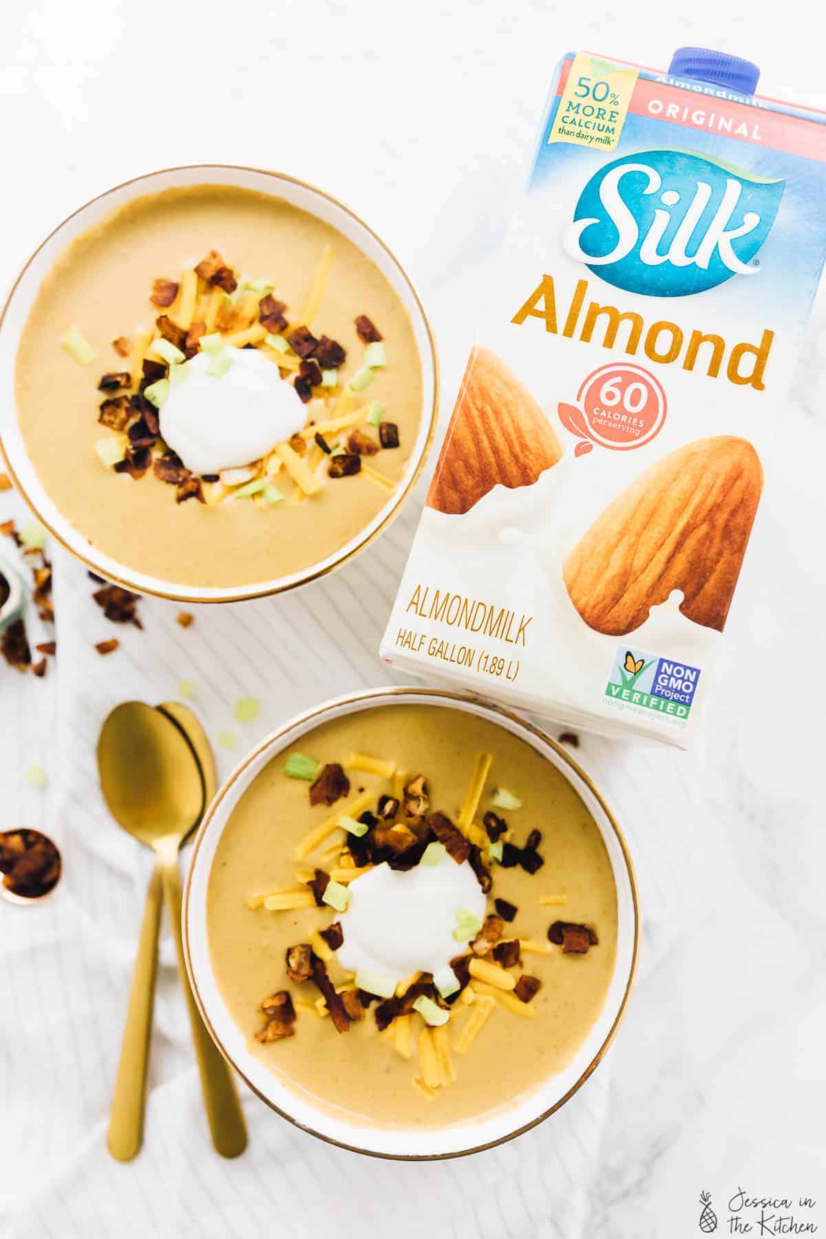 Vegan potato soup birds eye view with a carton of Silk Almond milk.