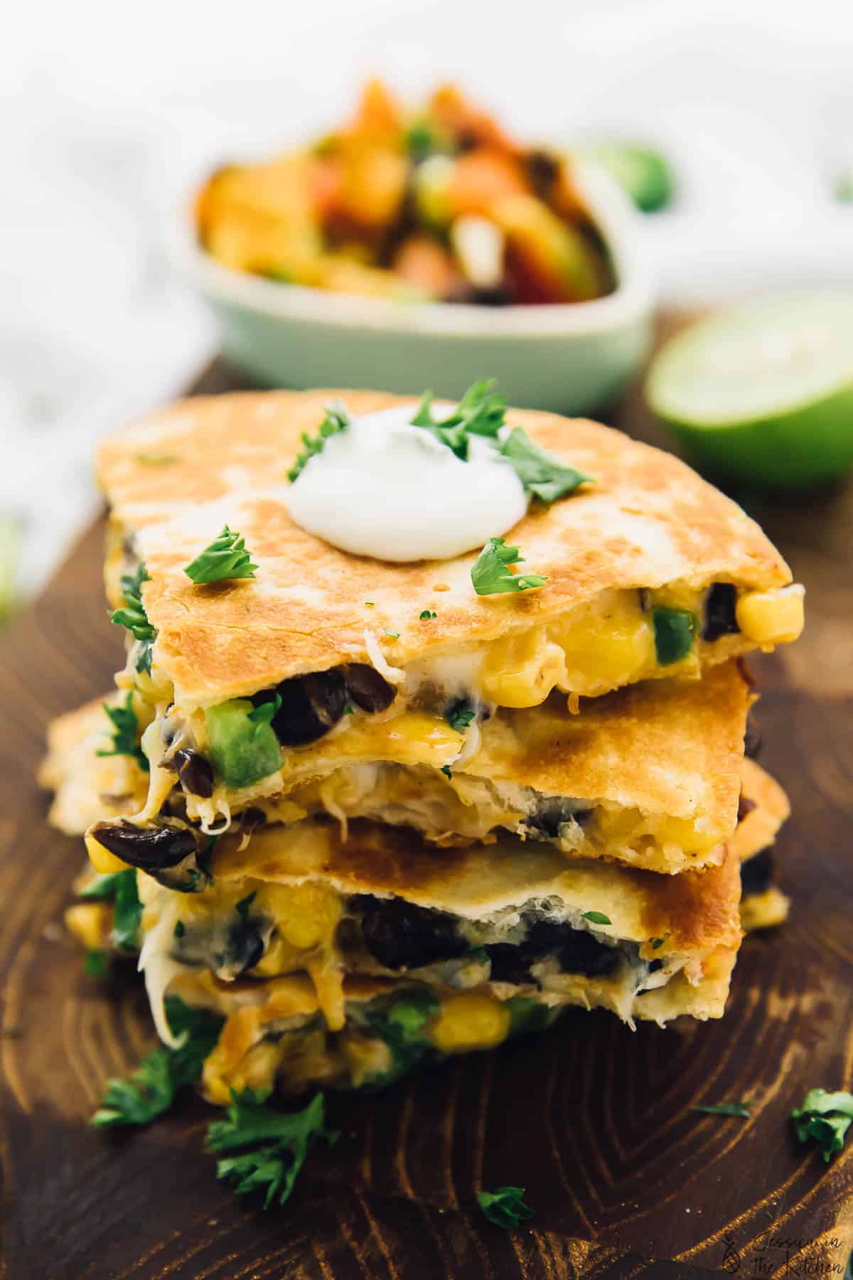 These easy black bean and corn quesadillas are done in just 15 minutes, making them perfect for a quick weeknight dinner! Stack of black bean and corn quesadilla wedges on wooden board
