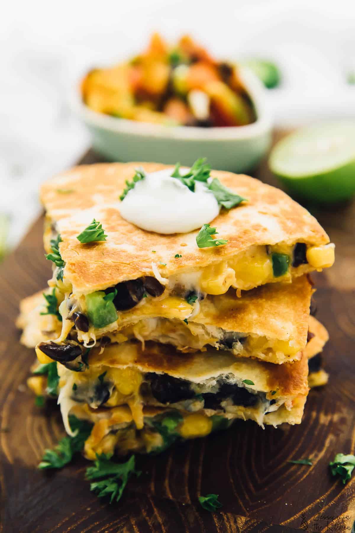 A stack of black bean and corn quesadillas on a wooden board. 