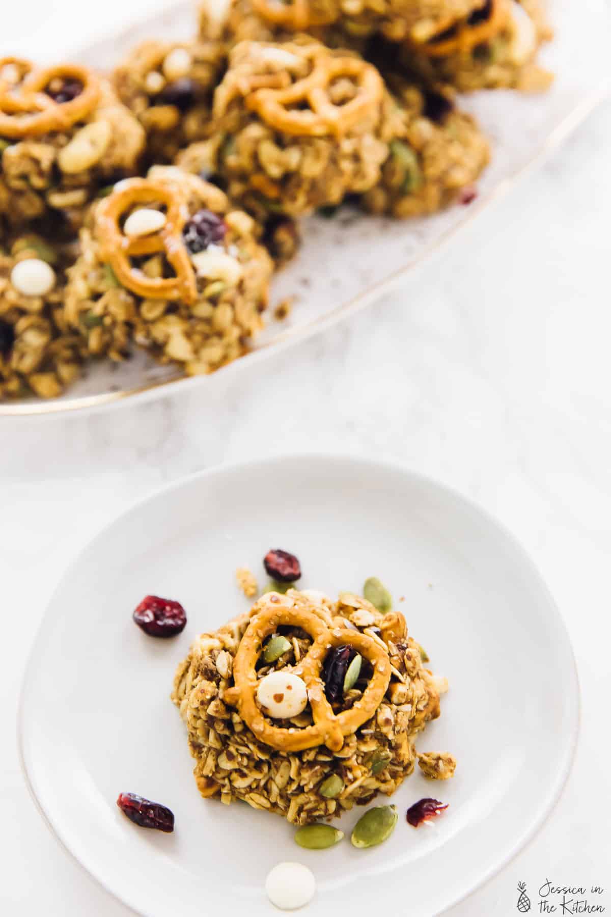 A trail mix cookie on a plate with more cookies in the background. 