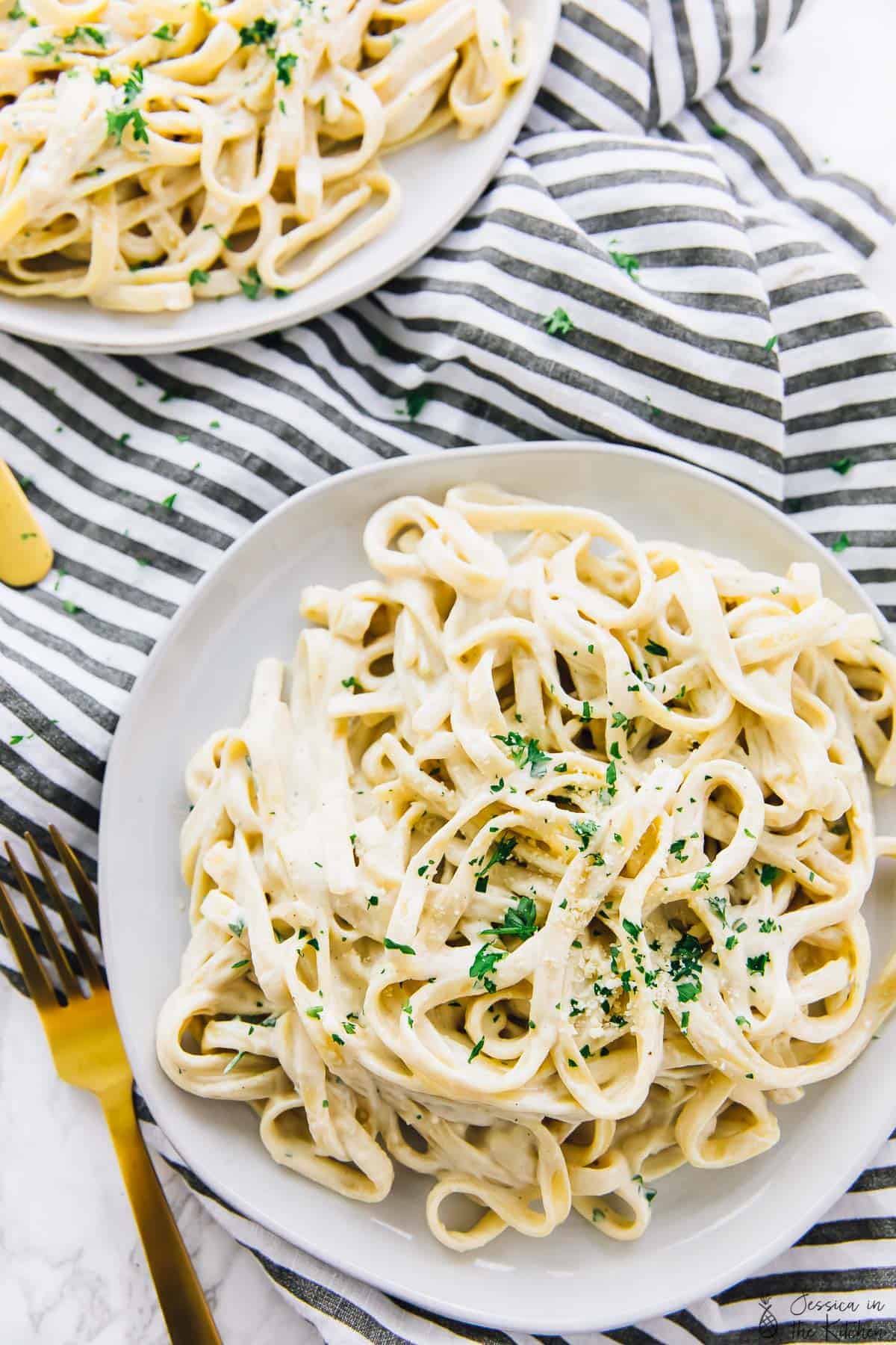 Vegan garlic Alfredo pasta in a plate with chopped parsley on on top.