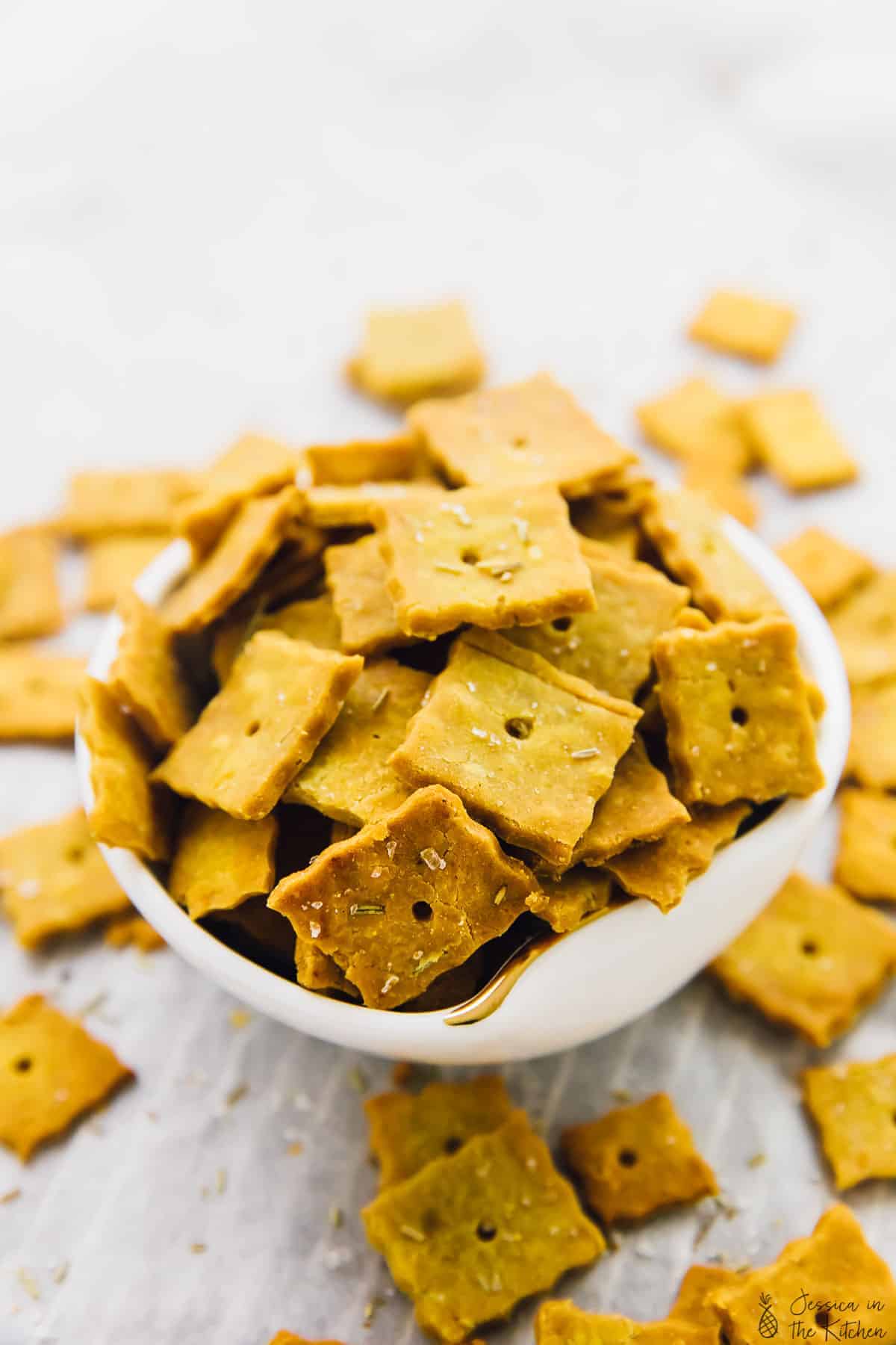 A bowl of herbed parmesan crackers, surrounded by more crackers. 