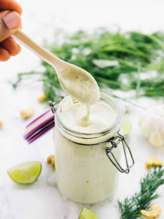 A spoon dipping into ranch dressing in a jar.