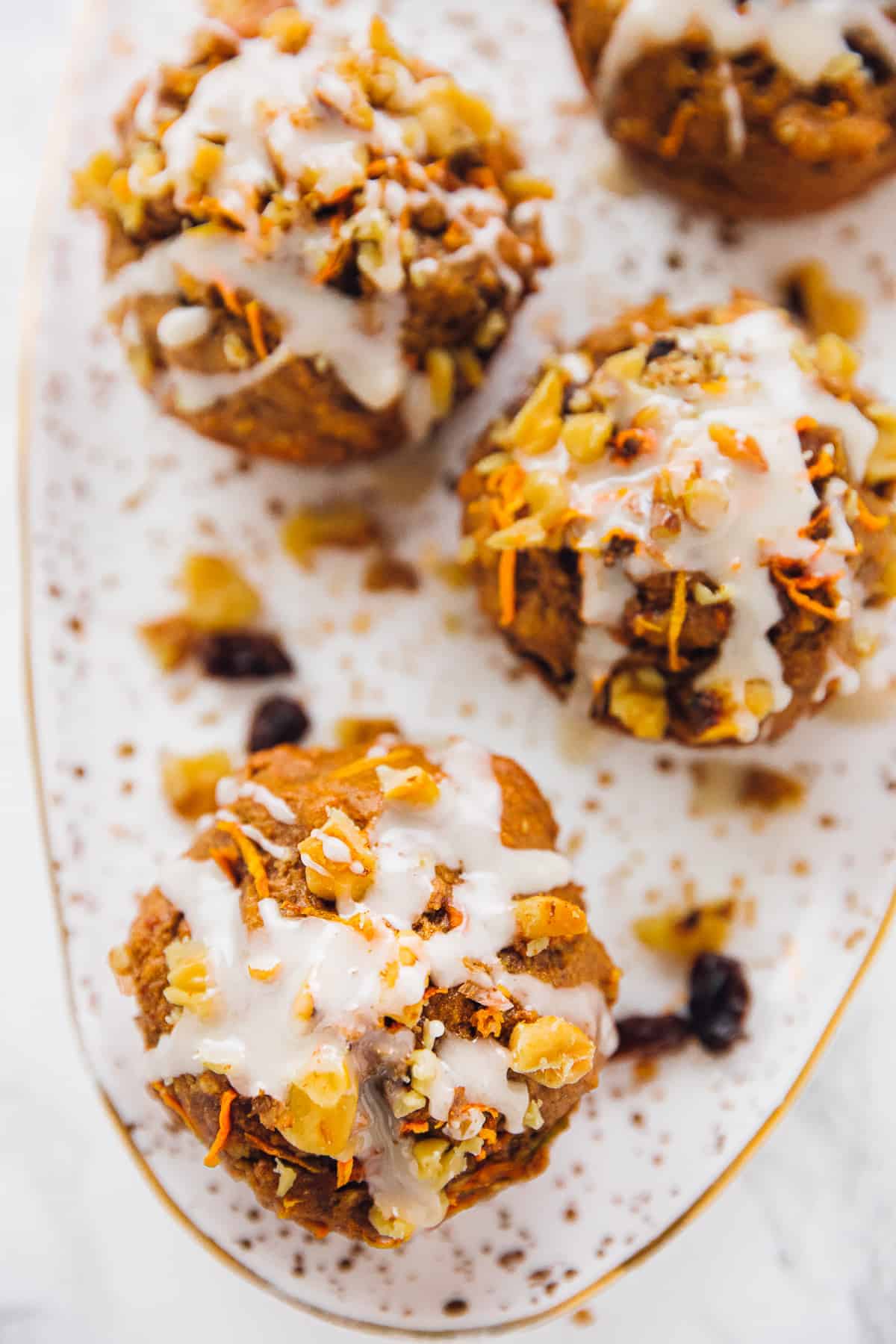carrot cake muffins with icing lined up on a white and gold plate