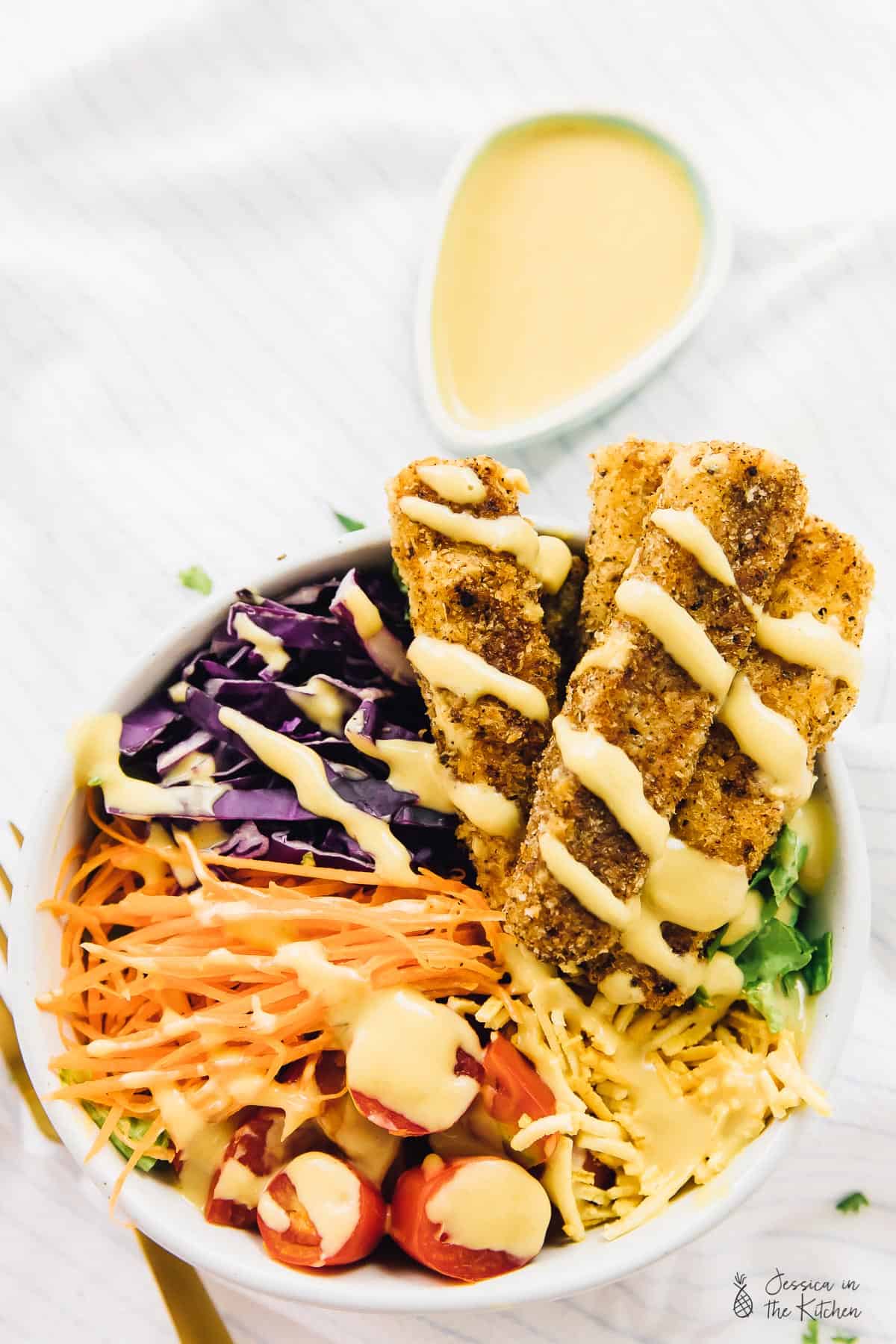 Overhead view of vegan crispy cajun fried chicken salad, drizzled with honey mustard dressing.