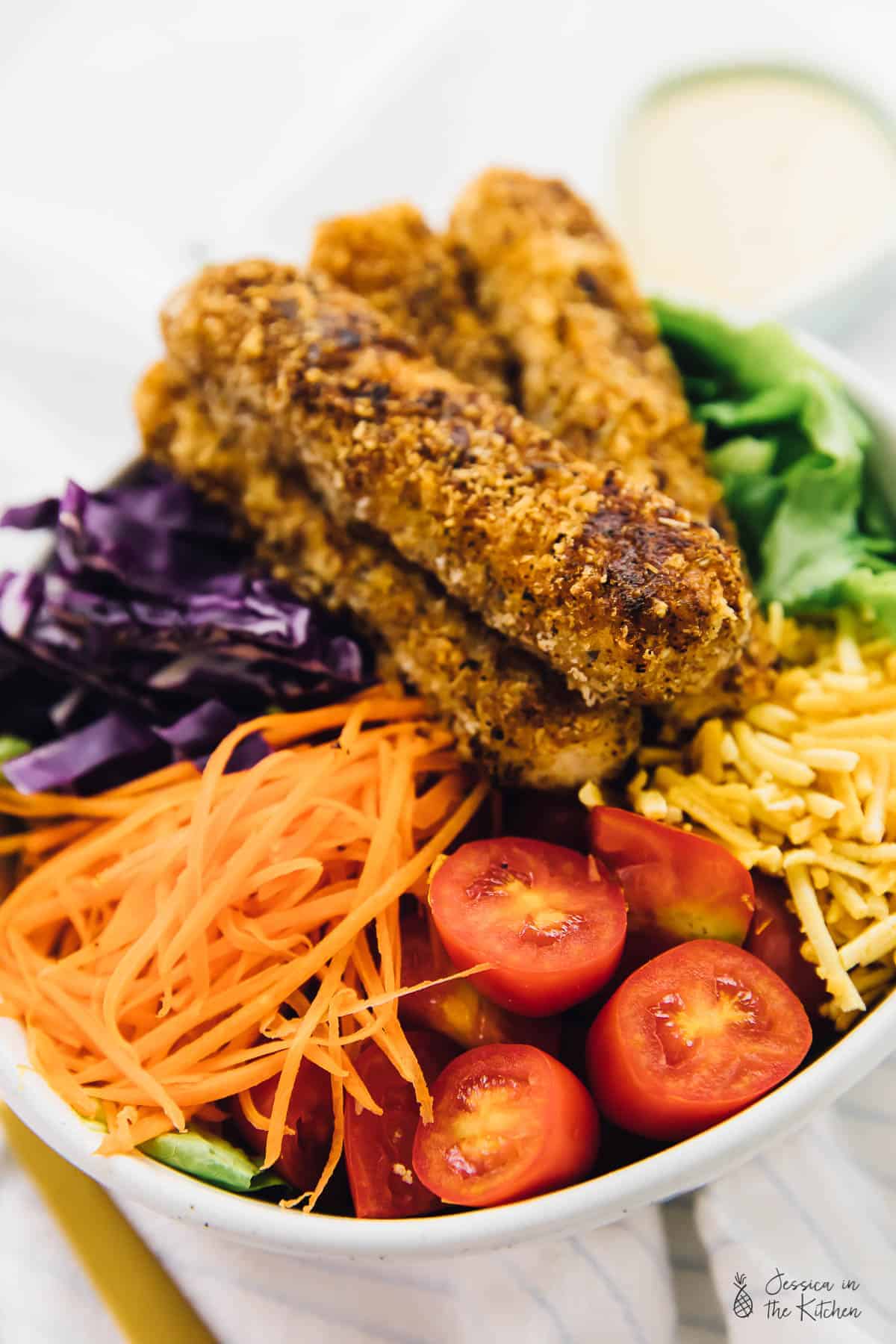 Vegan fried chicken salad in a white bowl.