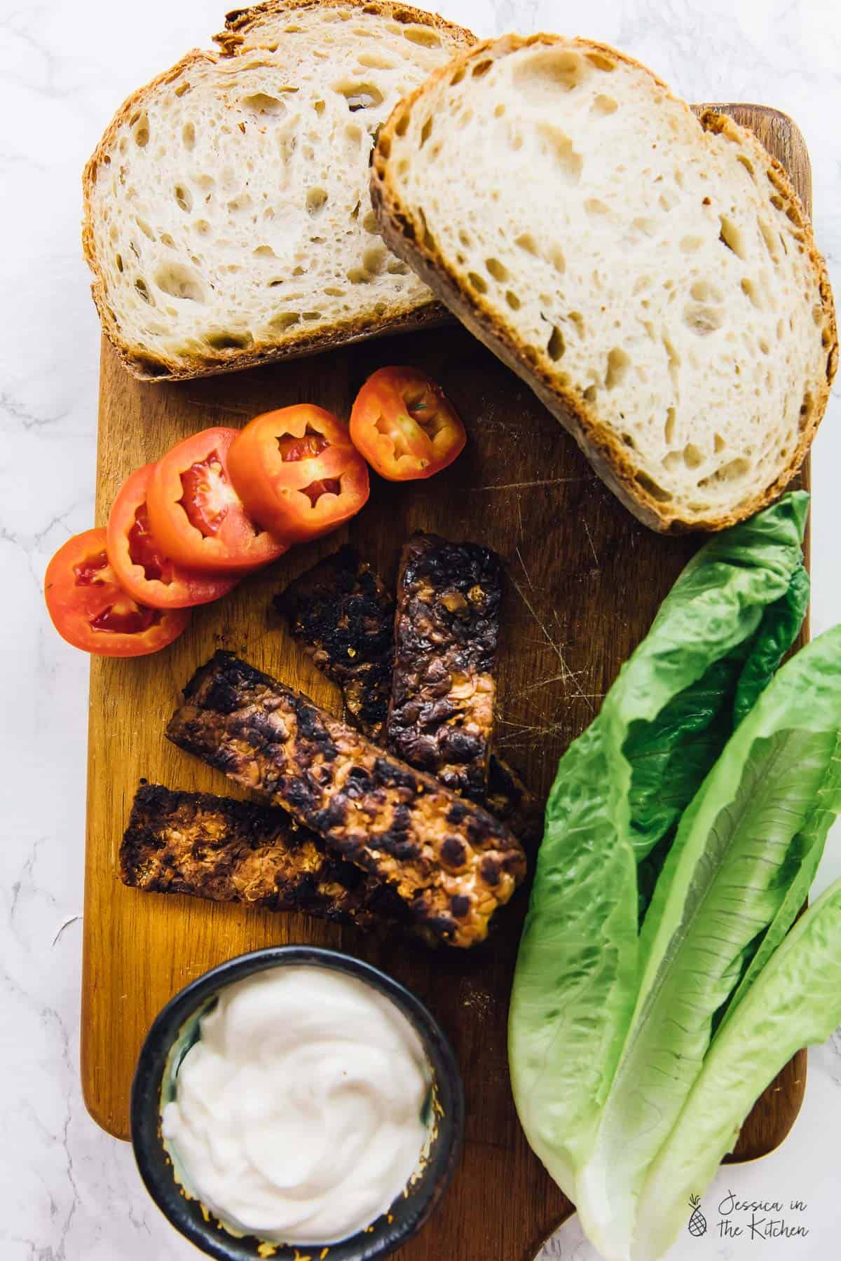 Top down view of ingredients for a bacon blt sandwich, on a wood board, 