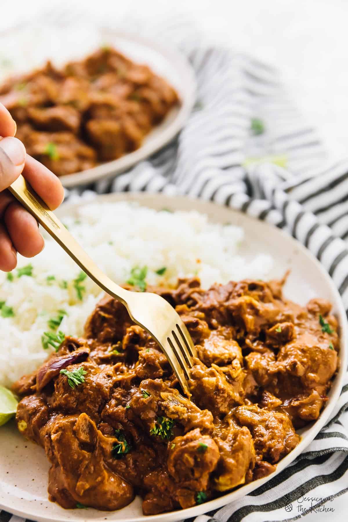 A fork dipping into vegan butter chicken with rice.